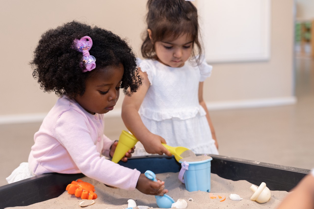 Meisjes spelen aan een zandtafel bij kinderdagverblijf gro-up
