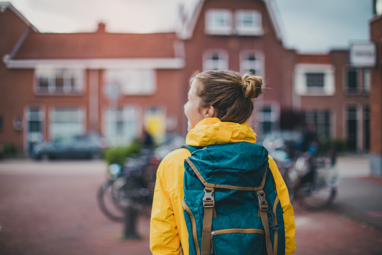 gro-up kinderen meisje met een gele jas en een rugtas loop op straat