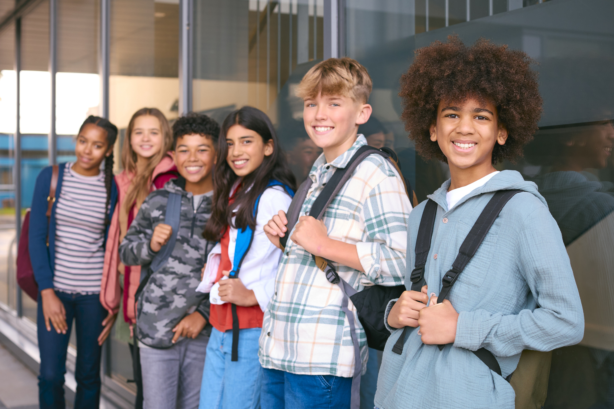 Groepje middelbareschooljongeren leunt tegen de muur in de gang