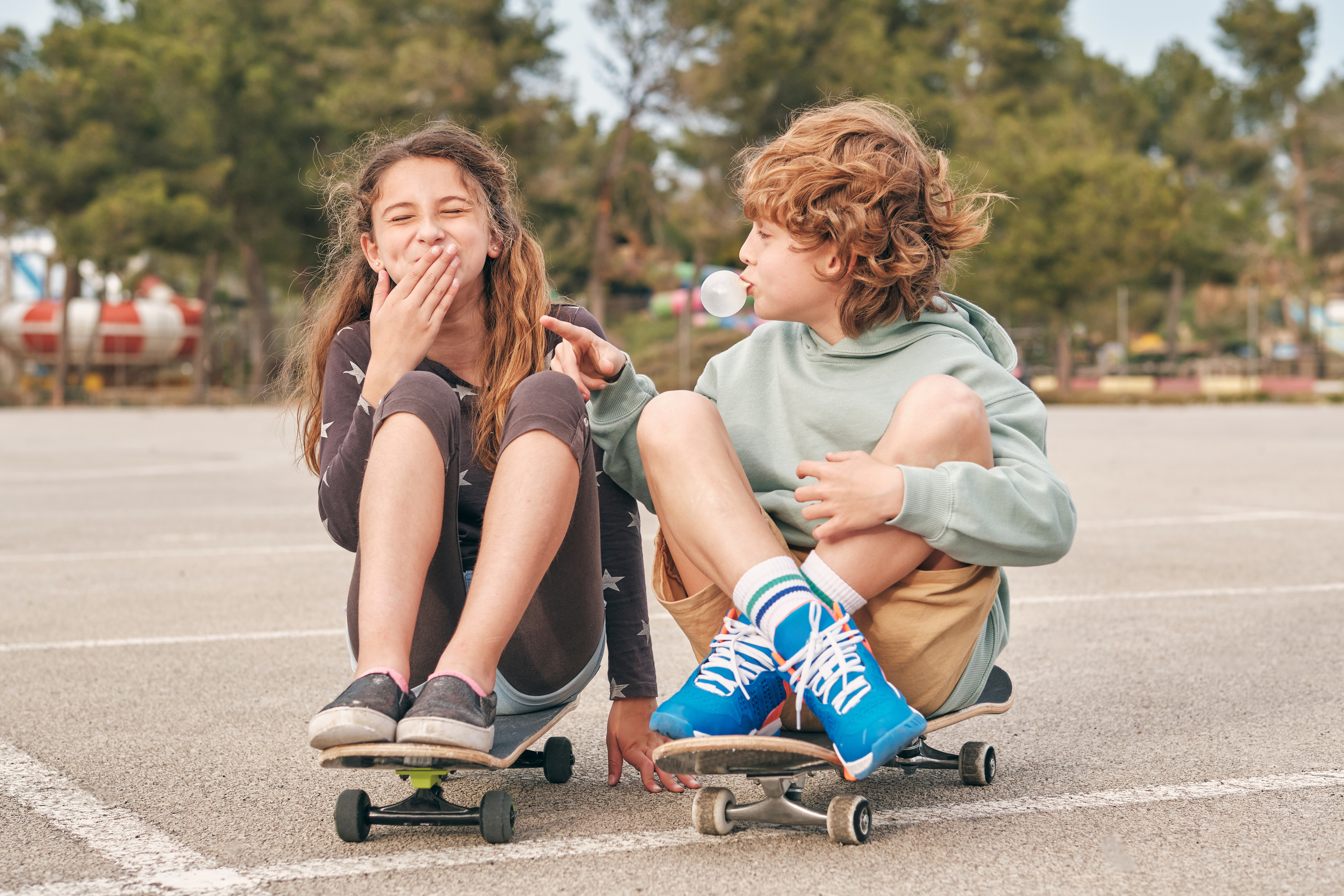Een jongen en meisje zitten op een skateboard en lachen met elkaar