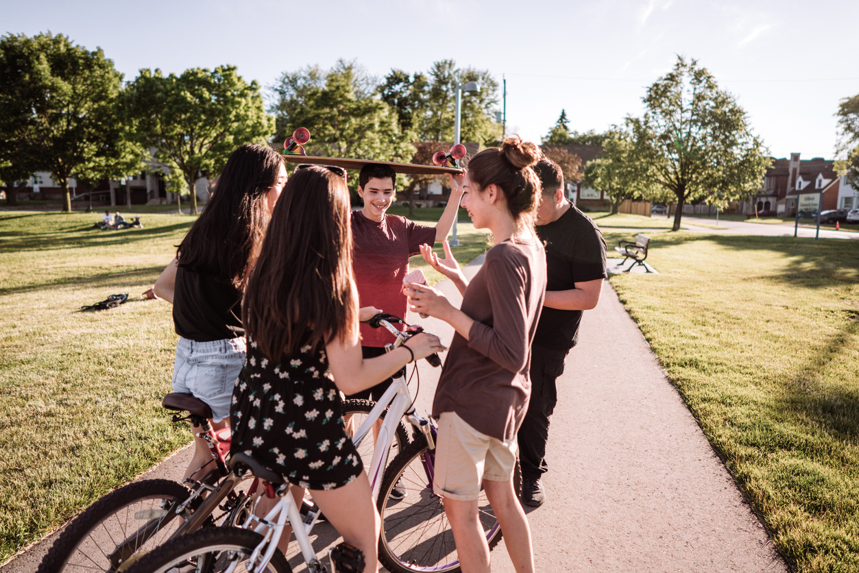 Jongeren praten met elkaar in een park in De Esch, sommige op de fiets, een met ene skateboard