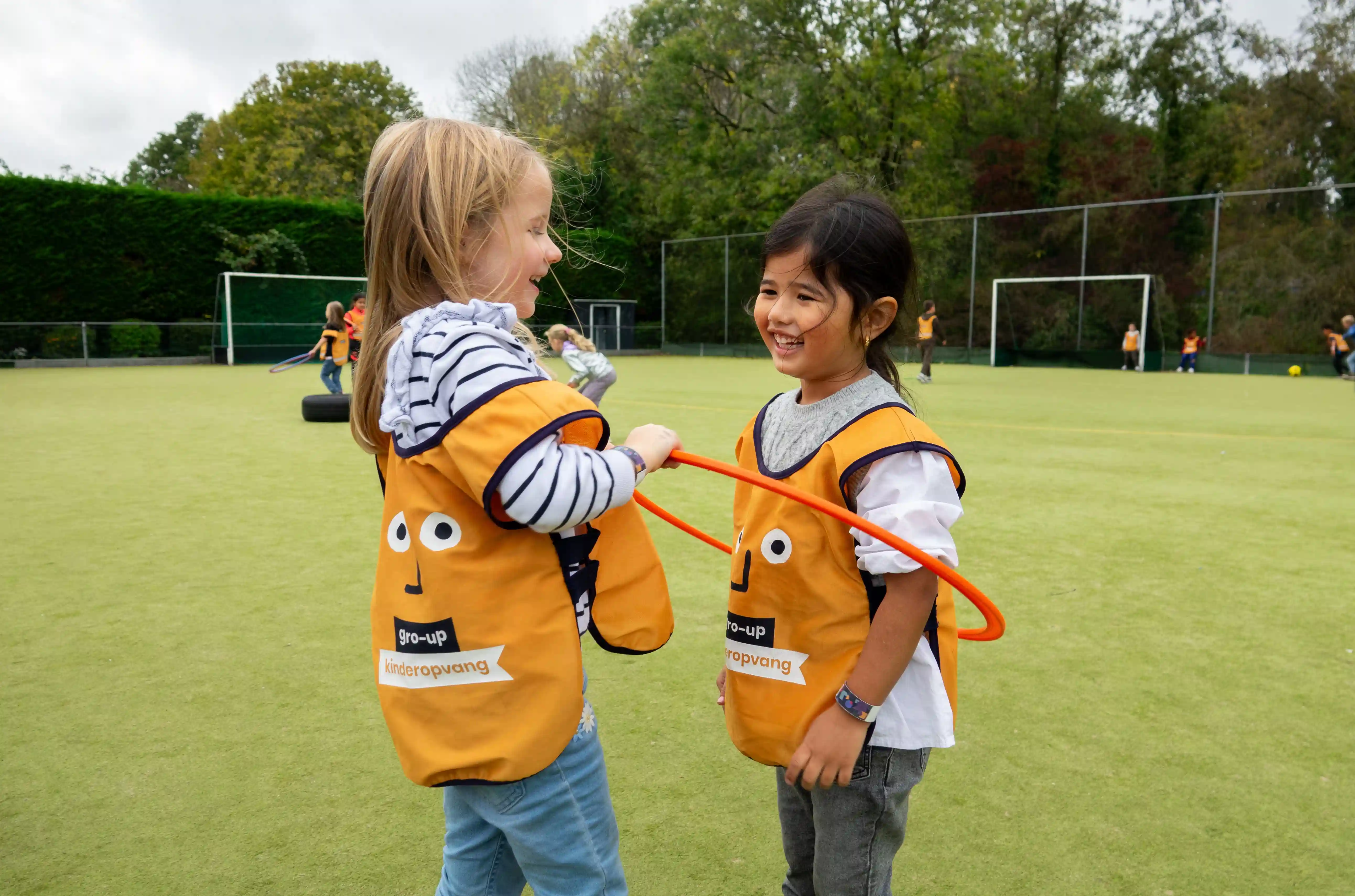 Twee meisjes (peuter-kleuter) hoelahoepen op een sportveld