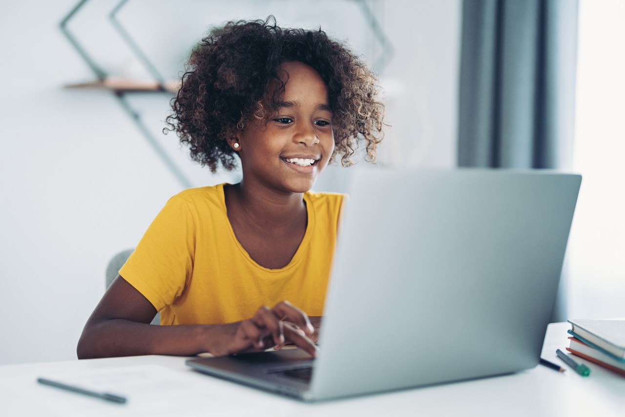 Tienermeisje zit achter een laptop en drukt op een knop