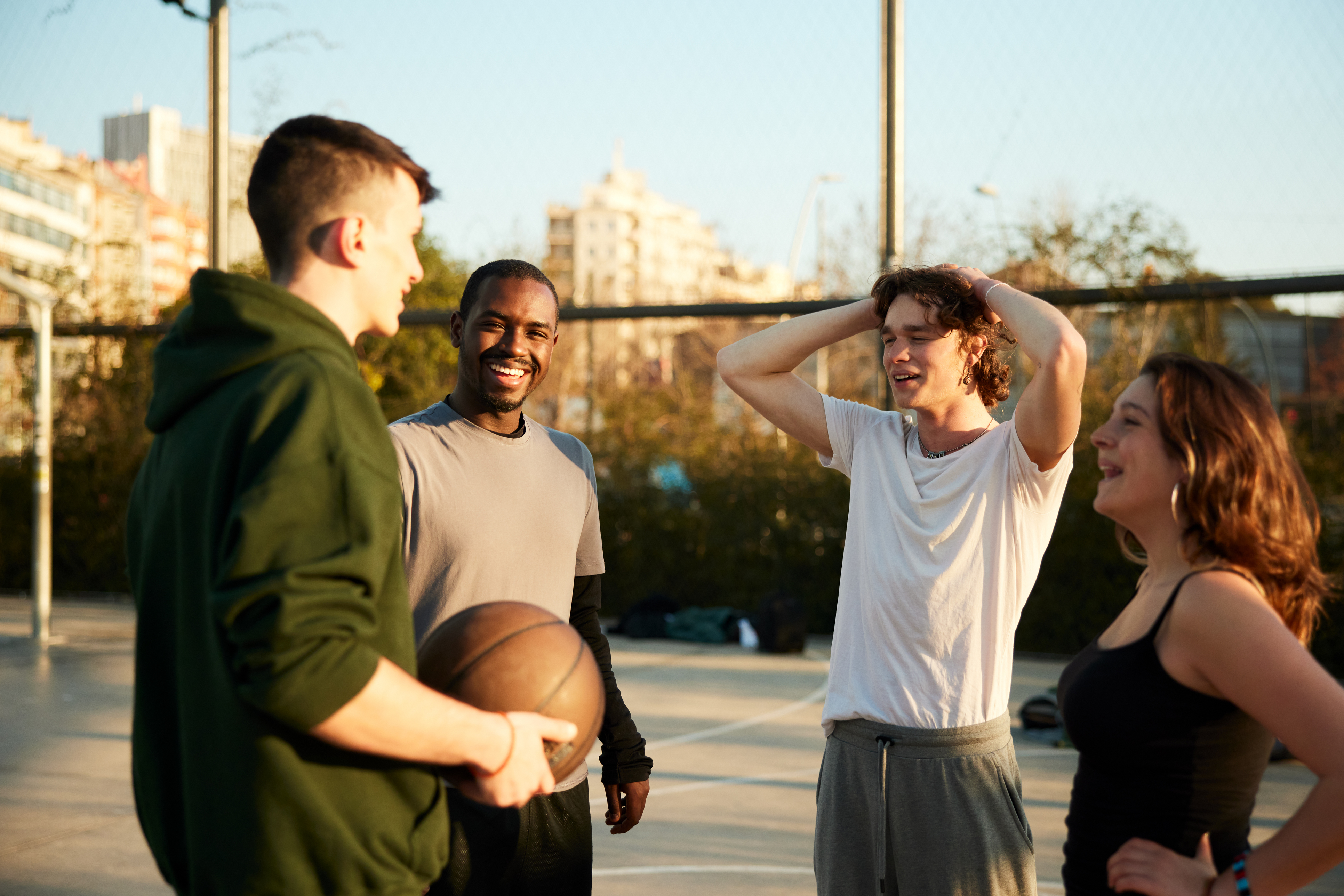 Vier jongeren praten met elkaar op een basketbalveld in Krimpenerwaard