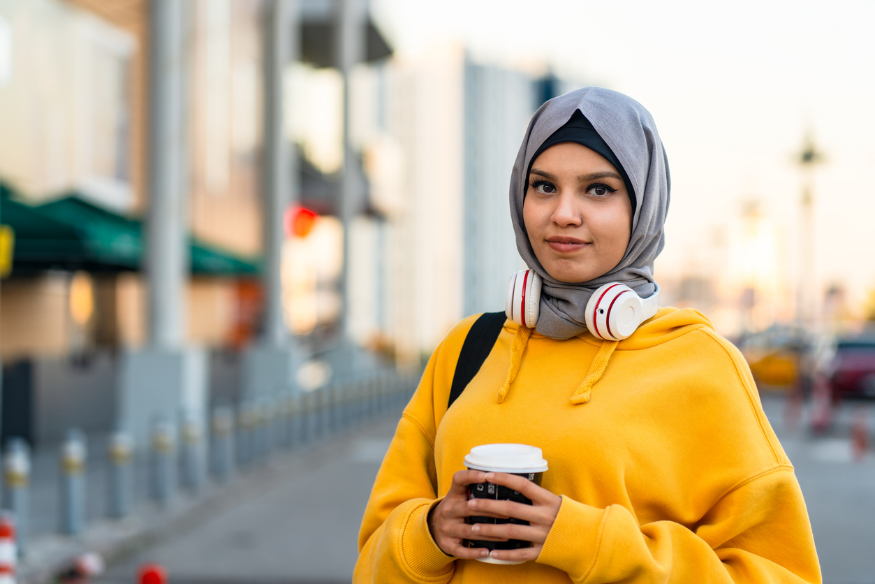 gro-up jeugd dame met koffie en een koptelefoon op straat