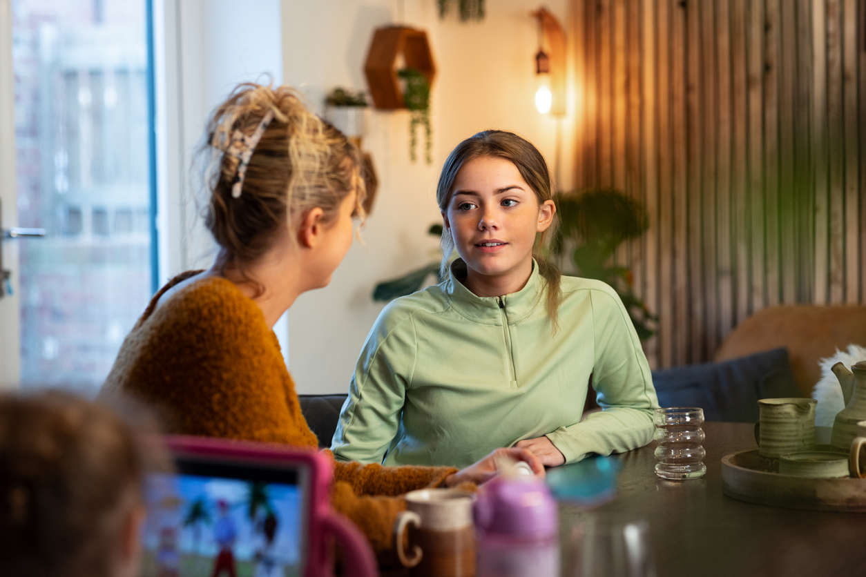 Meisje en moeder praten met elkaar aan de keukentafel over heftig nieuws