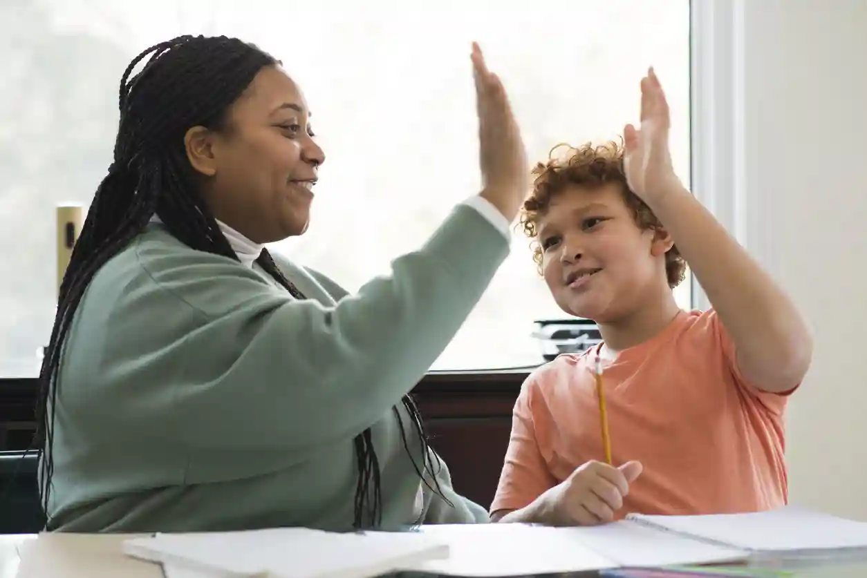 gro-up jeugdhulpverlener geeft een high five aan een jongen die schoolbegeleiding krijgt