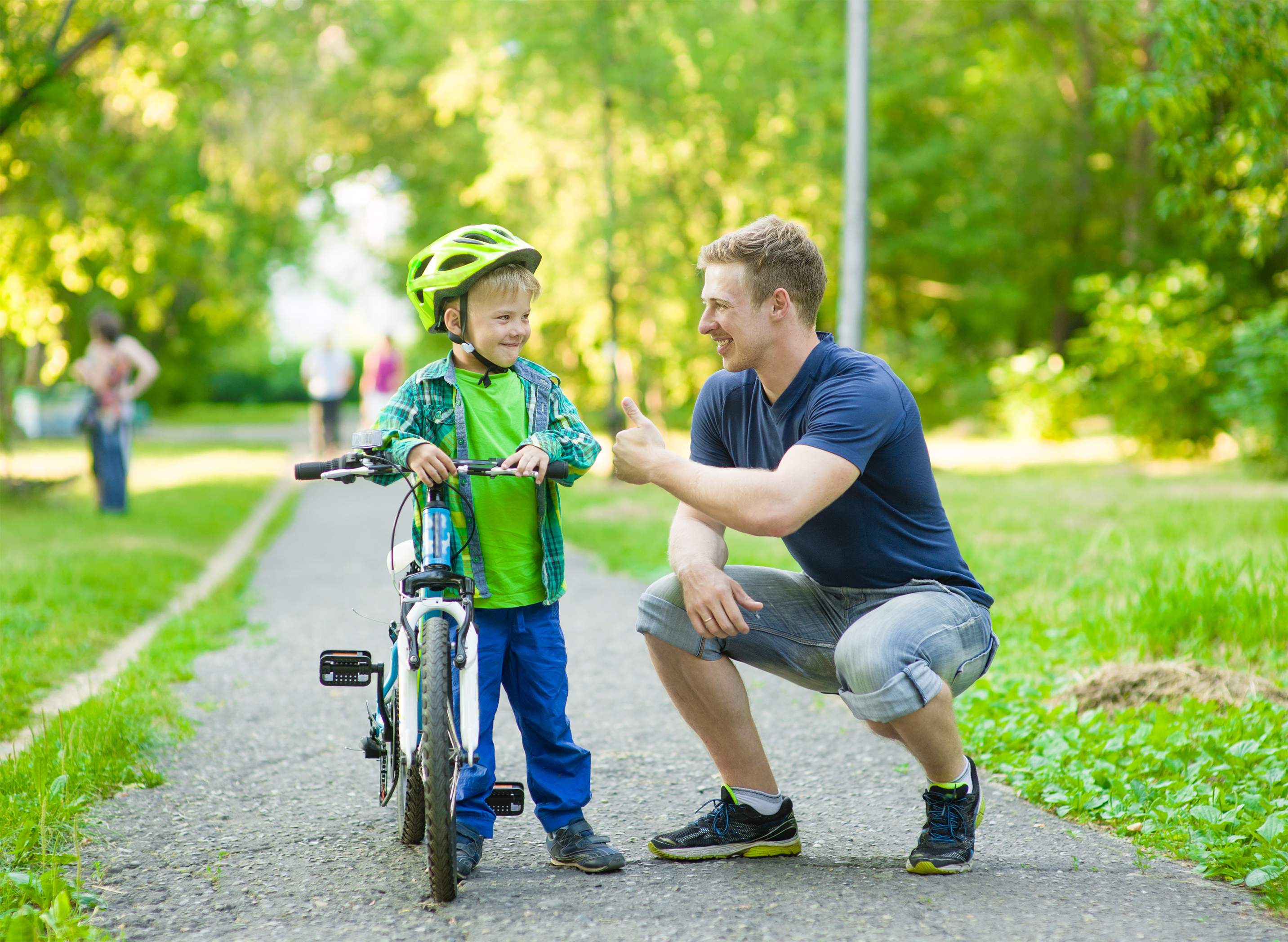 gro-up volwassene man geeft een compliment aan een jongen dat leert fietsen