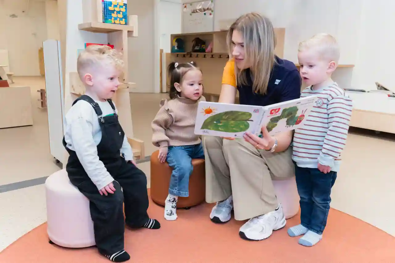 gro-up kinderen Drie peuters worden voorgelezen door een pedagogisch professional op een Inclusieve Kinderopvang in Den Haag