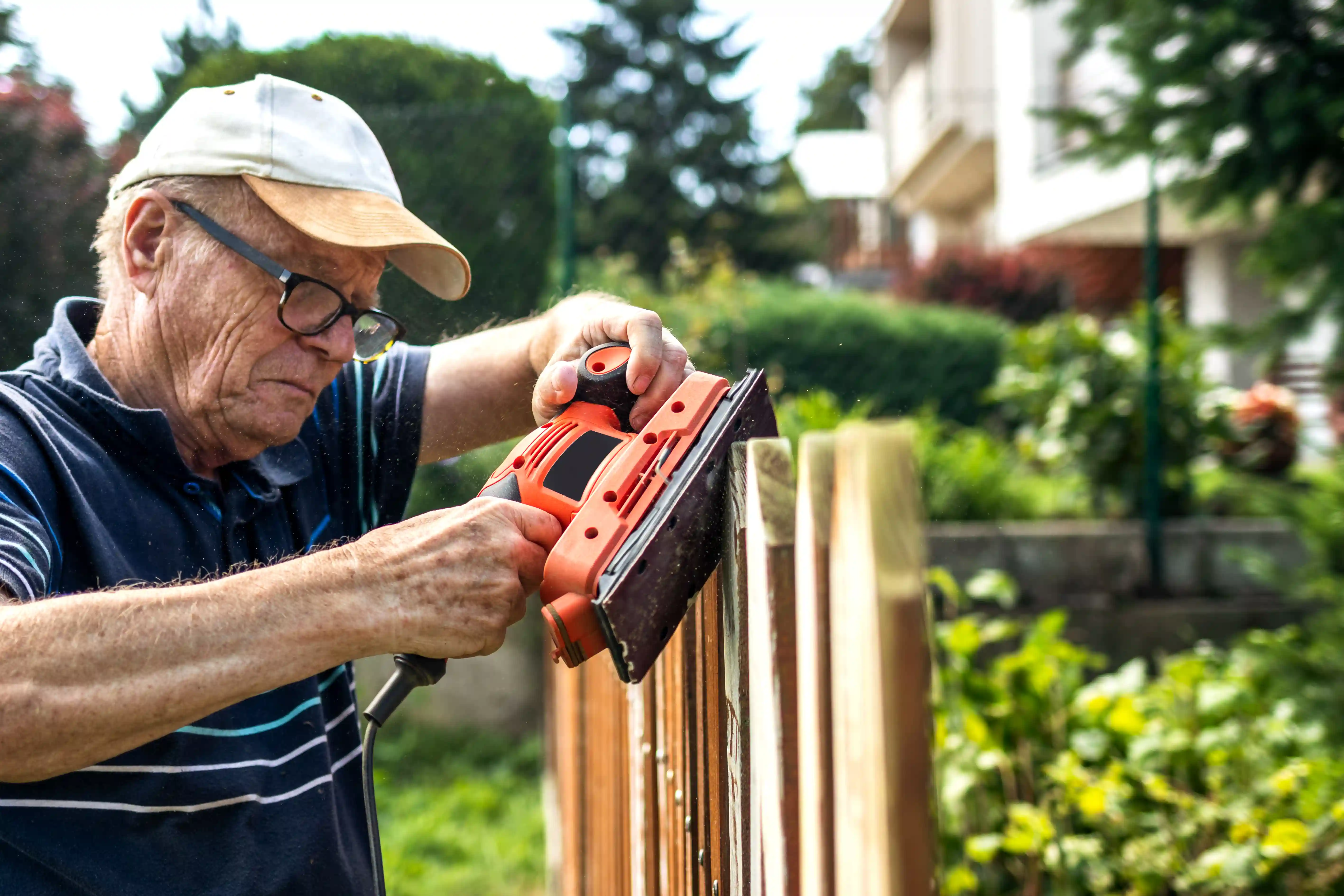 Een oude man schuurt een schutting als onderdeel van DemenTalent van gro-up buurtwerk