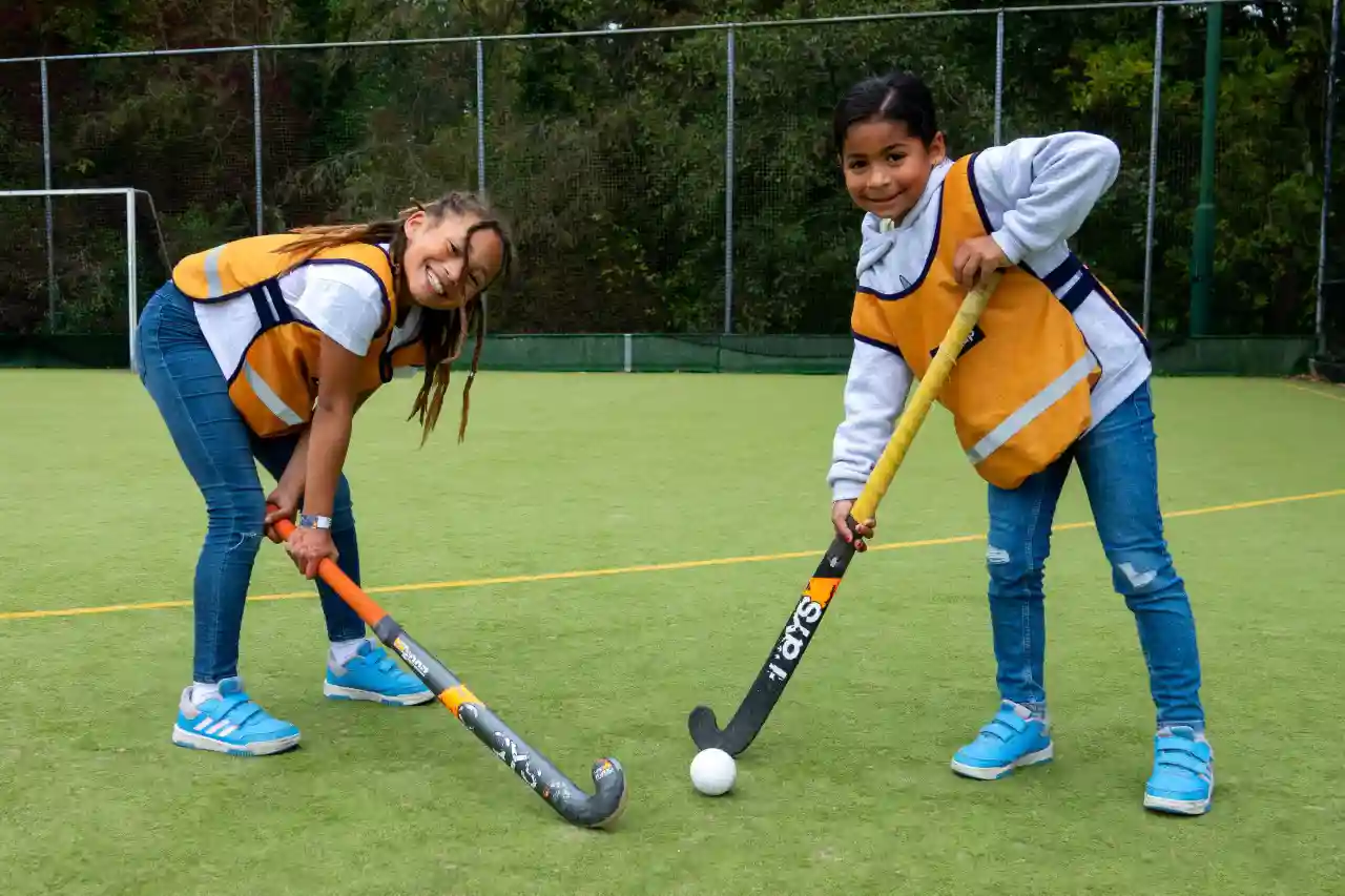 Twee (pré-)puber meisjes poseren met een hockeystick