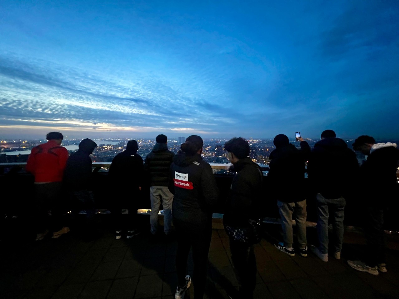 Jongeren kijken uit over Gouda bij nacht