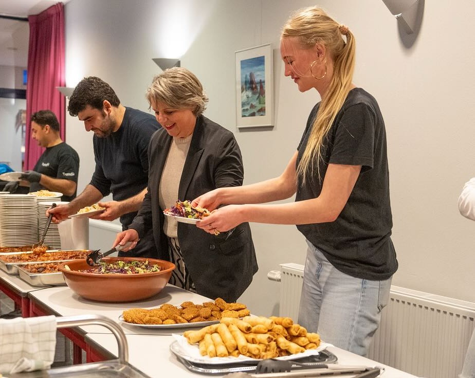 Mensen scheppen eten op tijdens een Iftar in Woerden georganiseerd door jongeren met hulp van gro-up buurtwerk