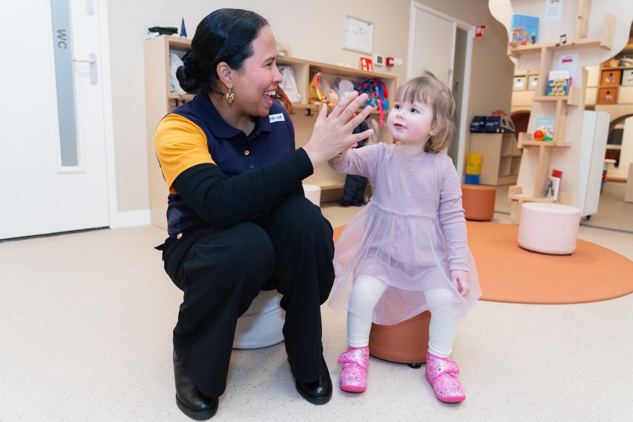 Meisje krijgt een high five van de pedagogisch professional op de Inclusieve Kinderopvang