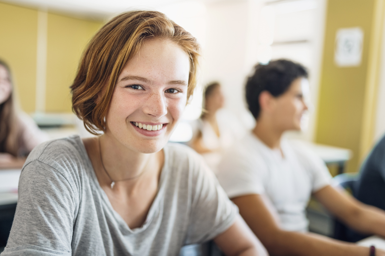 Tienermeisje lacht in de camera tijdens een les op school