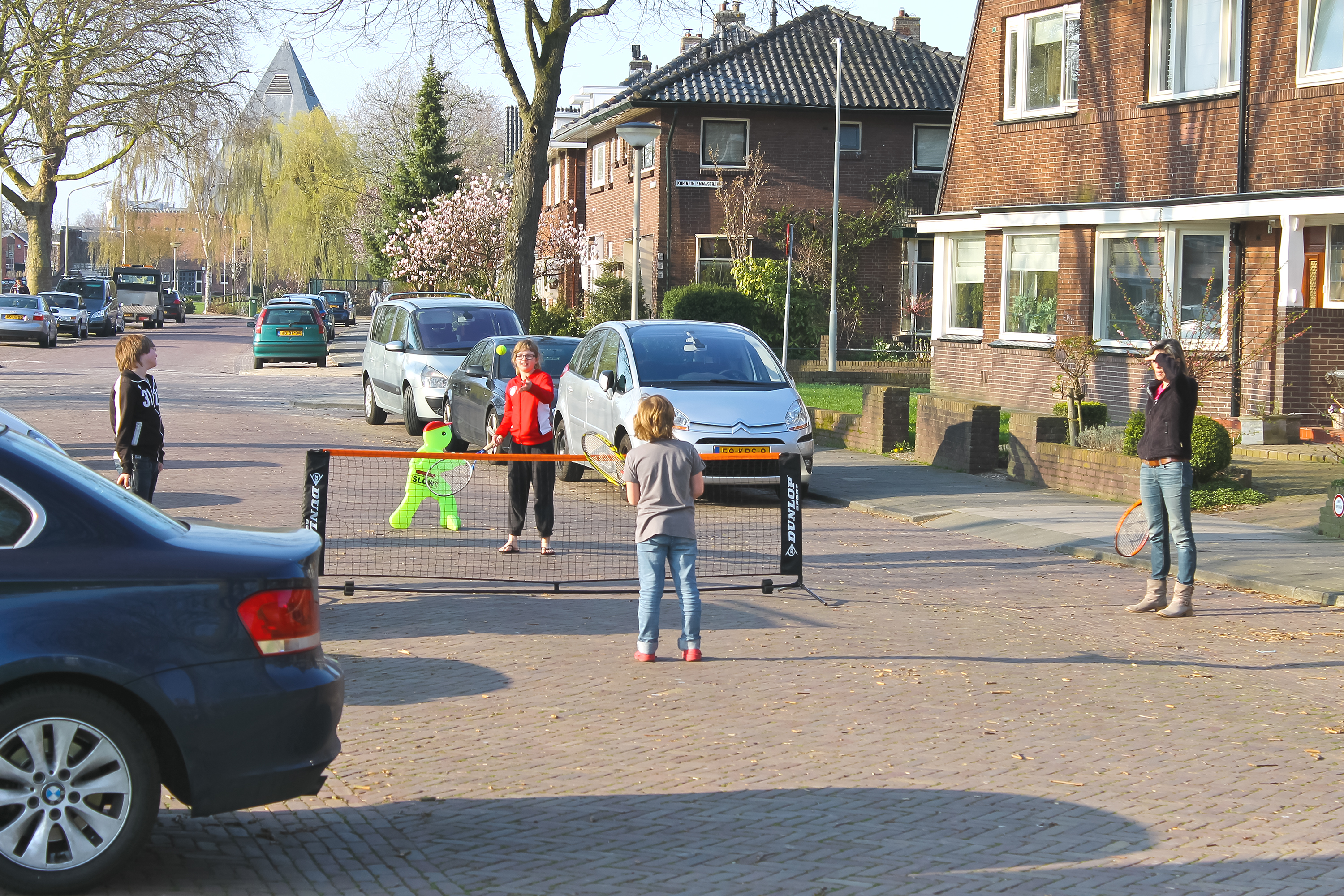 Drie kinderen en volwassen vrouw batmintonnen op straat in Krimpen aan den IJssel