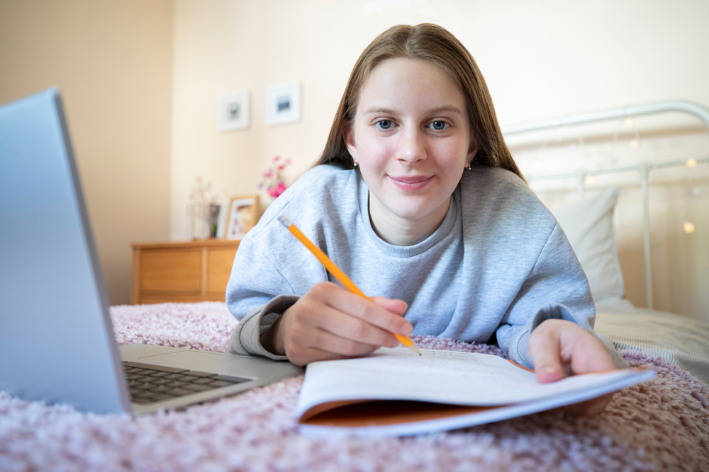 gro-up jeugd meisje maakt huiswerk op bed