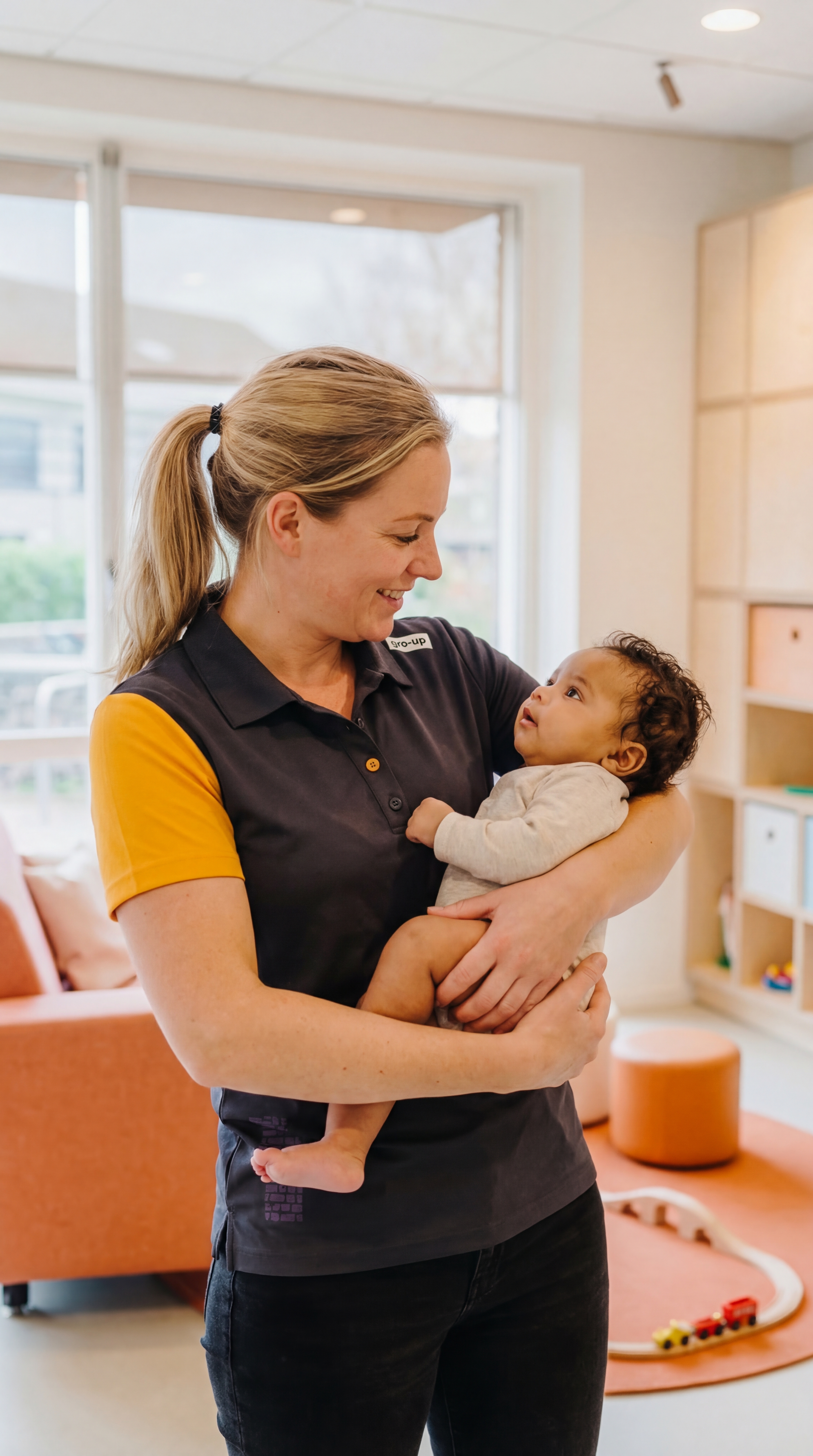 Baby wordt vastgehouden door pedagogisch professional lop kinderdagverblijf van gro-up