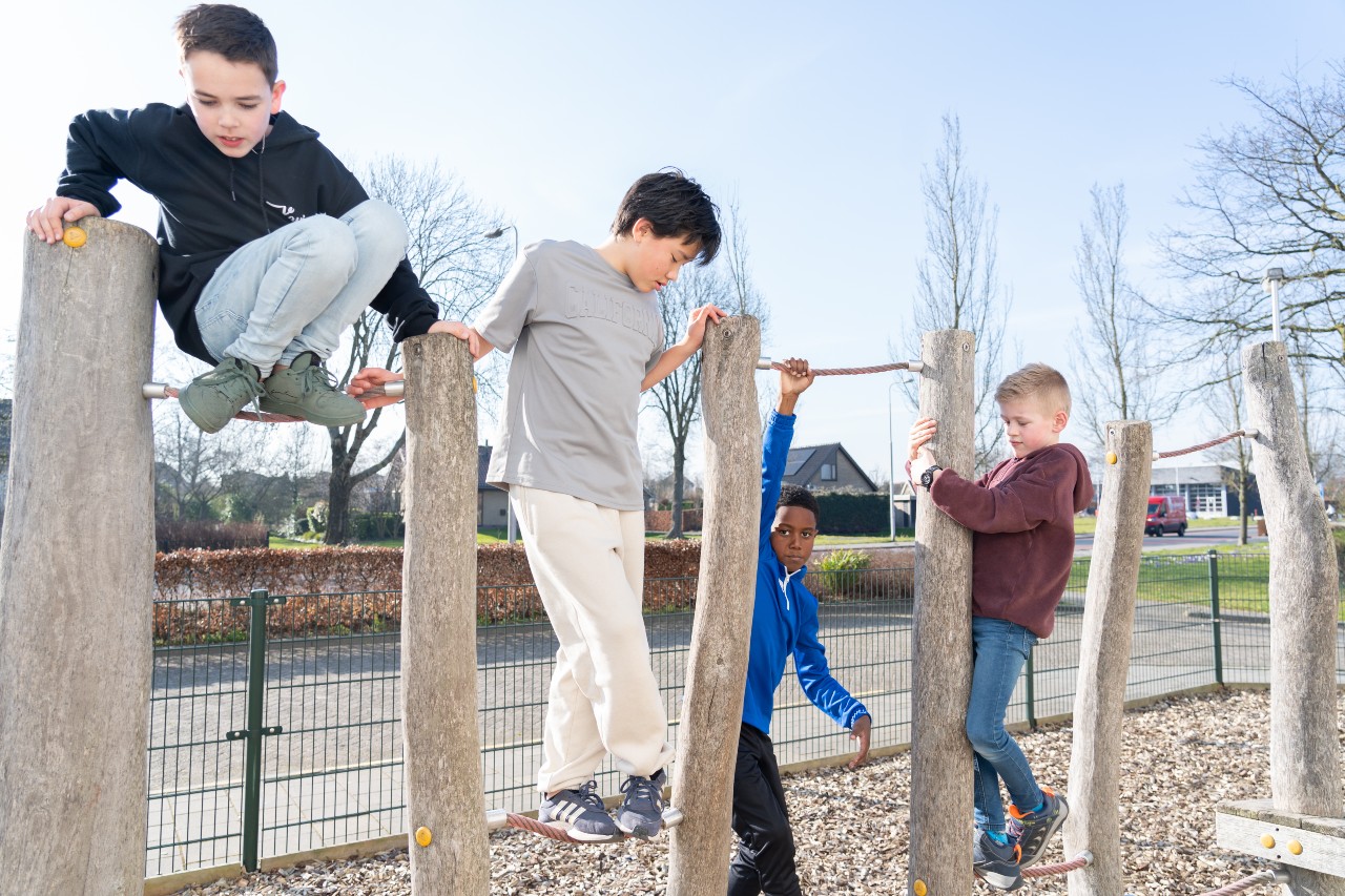 Vier jongens klimmen op een klimrek buiten bij buitenschoolse opvang Het Eendennest Schoutenhoek van gro-up in Zoetermeer