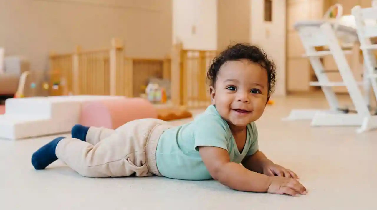 Baby kruipt lachend over de grond bij gro-up kinderdagverblijf Het Spectrum in Rotterdam Nesselande