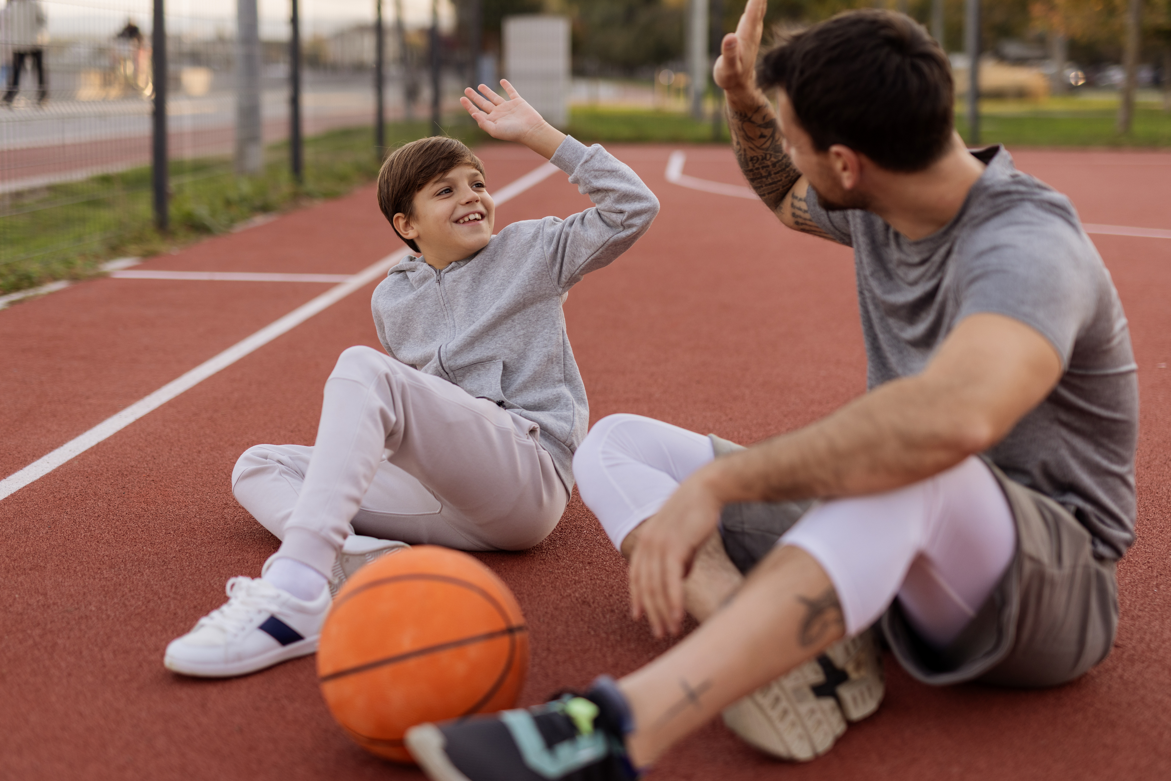 Jongen geeft een high five aan een jongerenwerker op een basketbalveld in Wassenaar